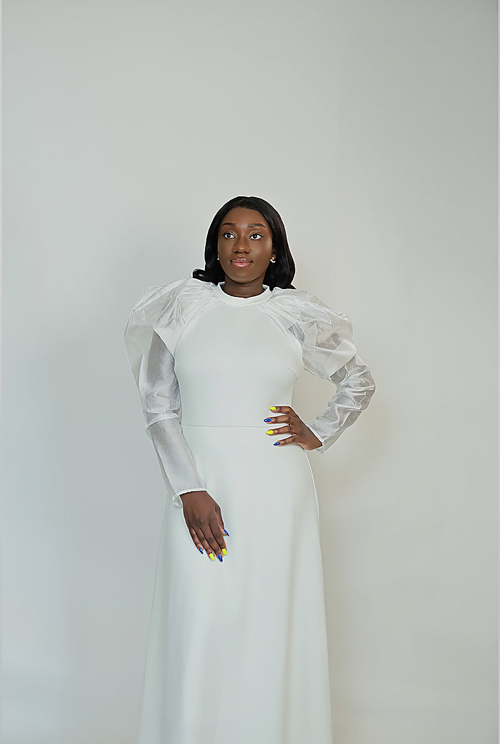 A full-length portrait on gray: a white gown with sheer puffed sleeves